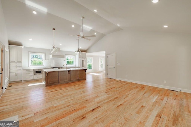 kitchen with high end refrigerator, light wood-type flooring, light countertops, and open floor plan