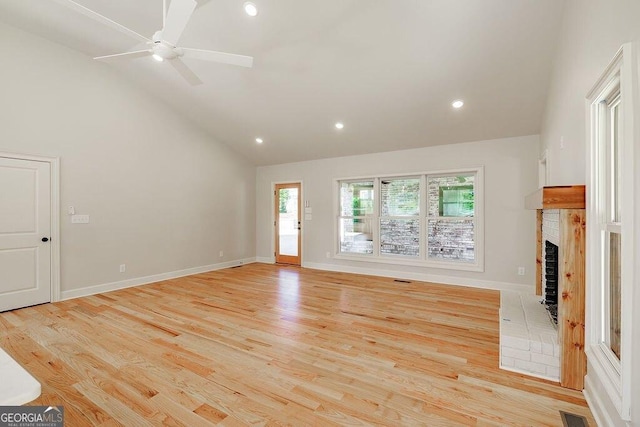 unfurnished living room featuring visible vents, baseboards, light wood-type flooring, a fireplace, and high vaulted ceiling