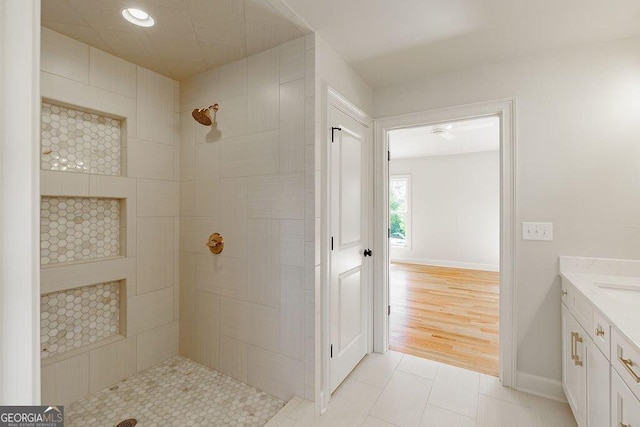 full bathroom with tile patterned floors, tiled shower, vanity, and baseboards