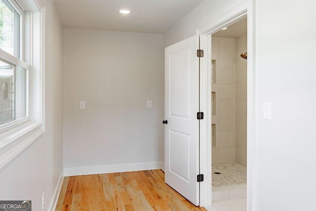 hall with light wood-style flooring and baseboards