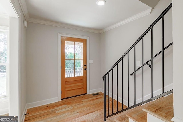 foyer featuring light wood-type flooring, baseboards, and ornamental molding