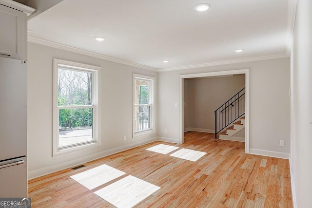 unfurnished room featuring light wood-type flooring, visible vents, and crown molding