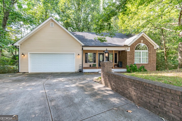 ranch-style home with an attached garage, a porch, driveway, and roof with shingles