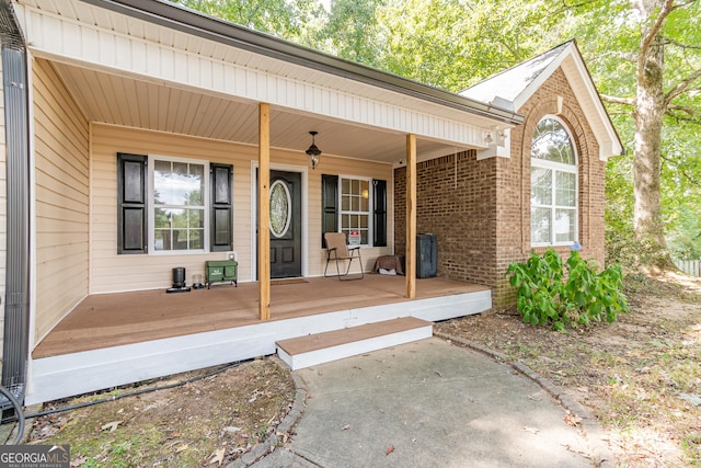 entrance to property with a porch and brick siding