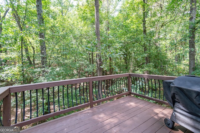 wooden terrace with a grill and a view of trees