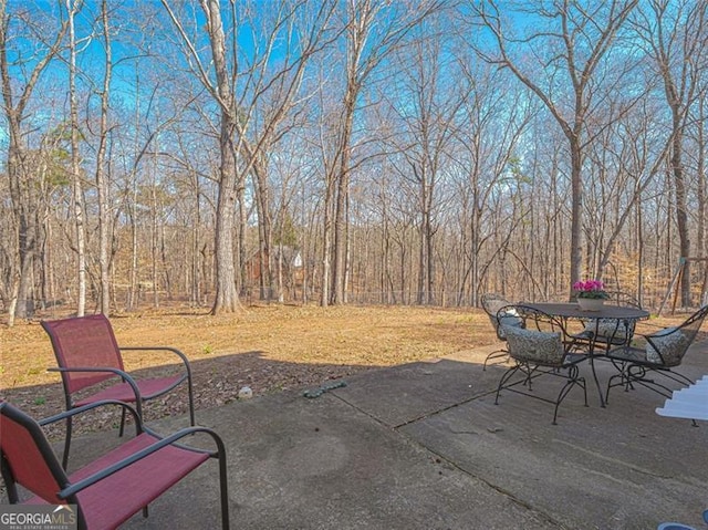 view of patio / terrace featuring outdoor dining space and a forest view