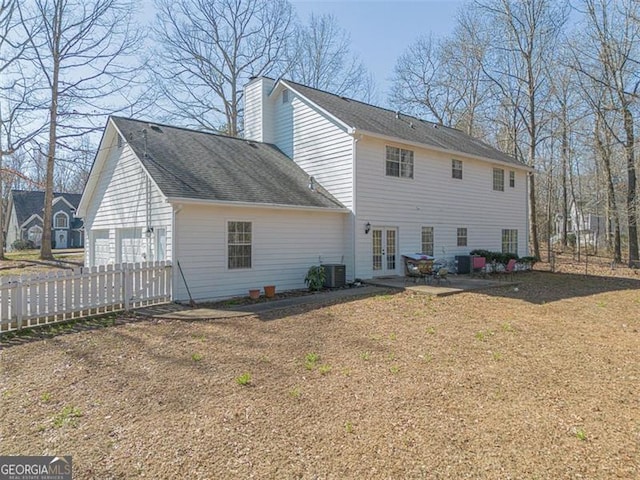 back of property featuring central AC unit, french doors, a garage, and a chimney