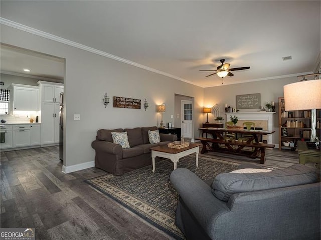 living area with dark wood-style floors, baseboards, crown molding, and ceiling fan