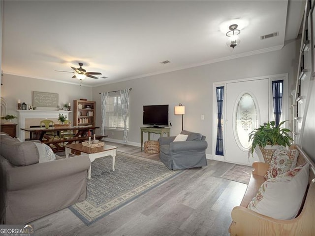 living room featuring visible vents, ornamental molding, ceiling fan, and wood finished floors