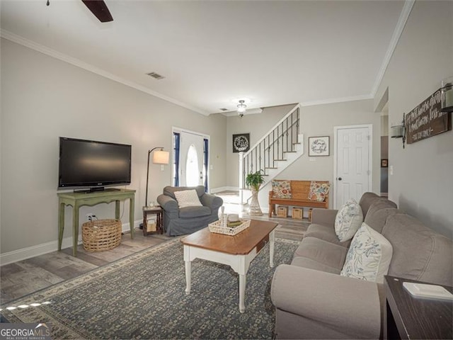 living room with a ceiling fan, wood finished floors, crown molding, baseboards, and stairs