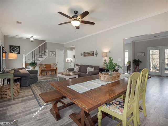 dining area featuring visible vents, ceiling fan, stairs, french doors, and wood finished floors