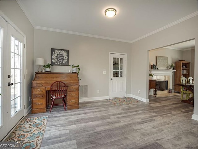 foyer entrance with visible vents, ornamental molding, a glass covered fireplace, wood finished floors, and baseboards