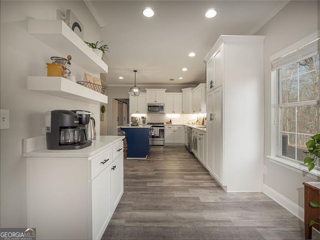 kitchen with tasteful backsplash, ornamental molding, stainless steel appliances, wood finished floors, and white cabinetry