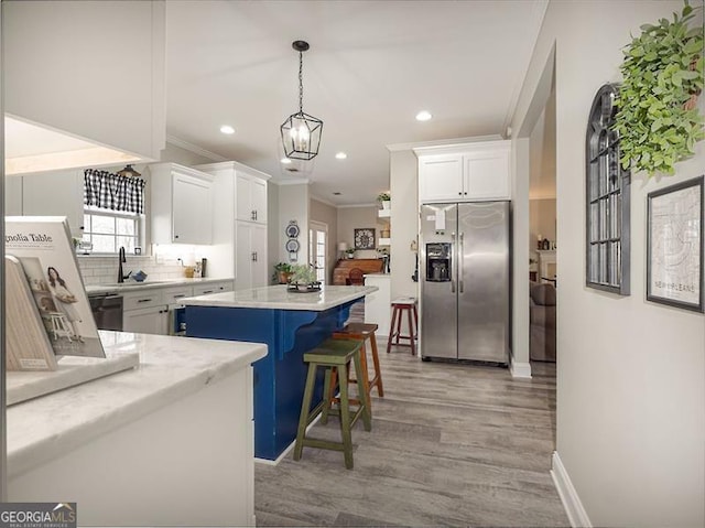 kitchen featuring white cabinets, ornamental molding, stainless steel refrigerator with ice dispenser, and a center island