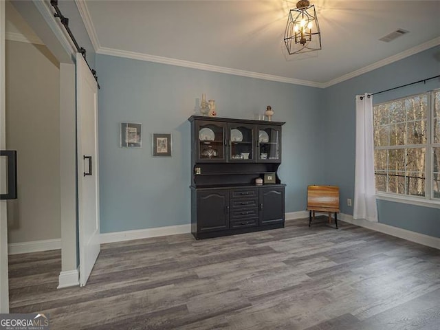 unfurnished room with a barn door, baseboards, wood finished floors, and ornamental molding