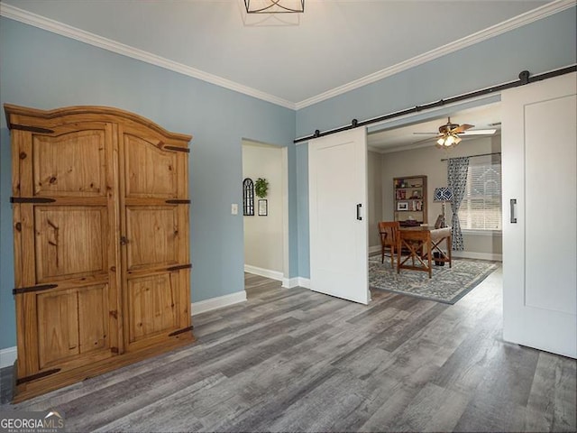 unfurnished room featuring ornamental molding, a ceiling fan, wood finished floors, a barn door, and baseboards