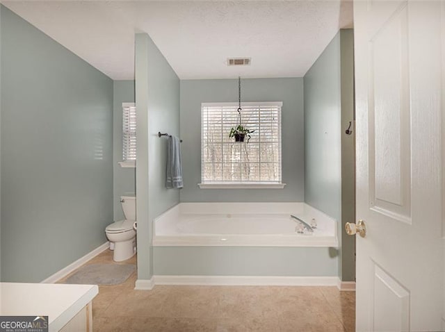 bathroom with visible vents, toilet, tile patterned flooring, baseboards, and a bath