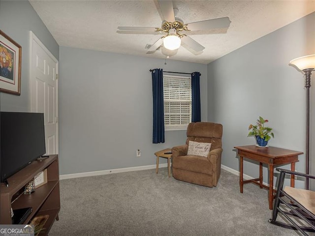 living area featuring ceiling fan, carpet flooring, baseboards, and a textured ceiling