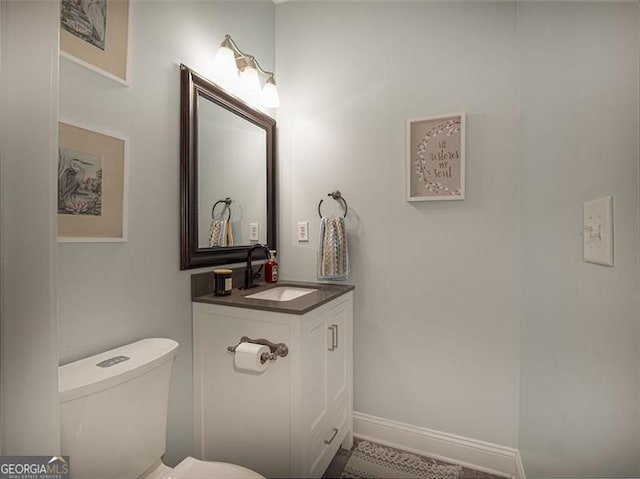 bathroom featuring toilet, vanity, and baseboards