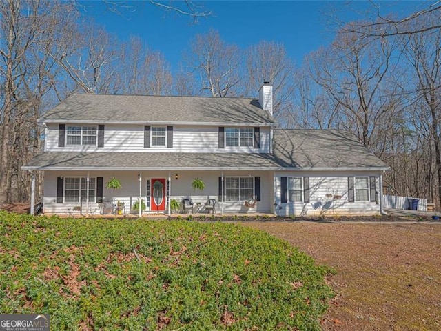 view of front of property with a porch, a front lawn, and a chimney