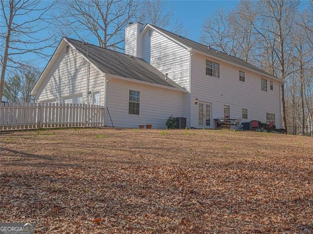 back of property with cooling unit, french doors, fence, and a chimney