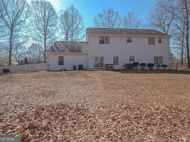 rear view of house with central air condition unit and fence