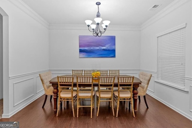 dining room featuring a notable chandelier, wood finished floors, visible vents, and ornamental molding