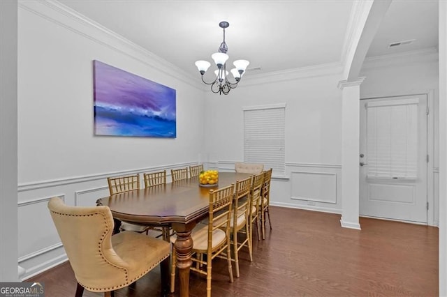 dining space with visible vents, a chandelier, ornamental molding, wood finished floors, and a decorative wall