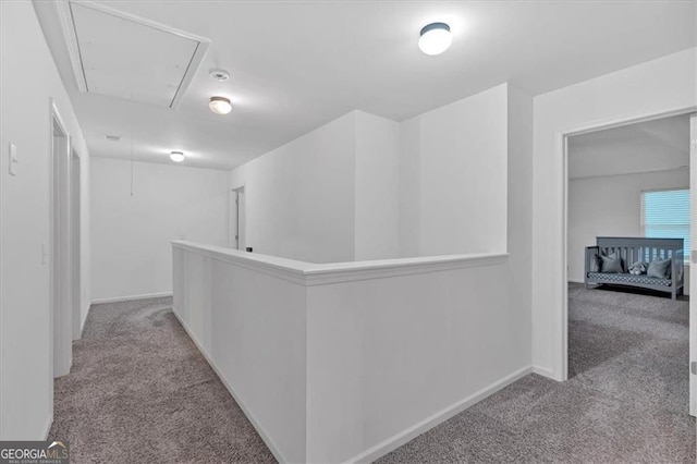 hallway with baseboards, an upstairs landing, attic access, and carpet flooring