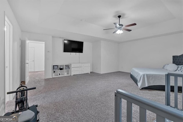 carpeted bedroom with a raised ceiling and a ceiling fan