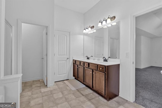 bathroom with a sink, baseboards, and double vanity