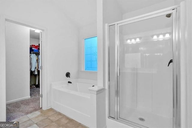 bathroom featuring a walk in closet, a shower stall, and a bath