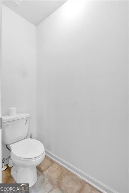 bathroom with baseboards, toilet, and tile patterned flooring