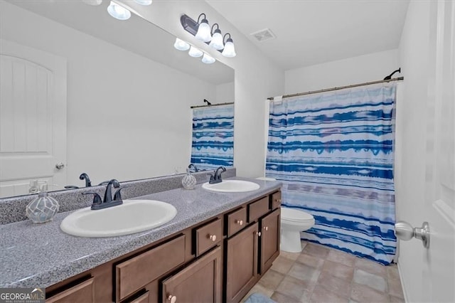 bathroom with double vanity, visible vents, toilet, and a sink