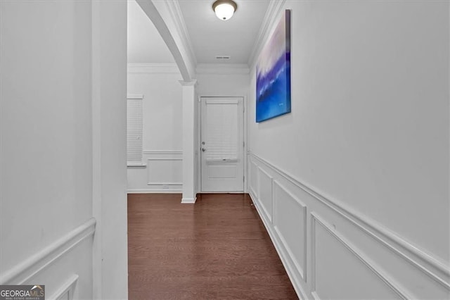 corridor with visible vents, ornamental molding, dark wood-style floors, arched walkways, and a decorative wall