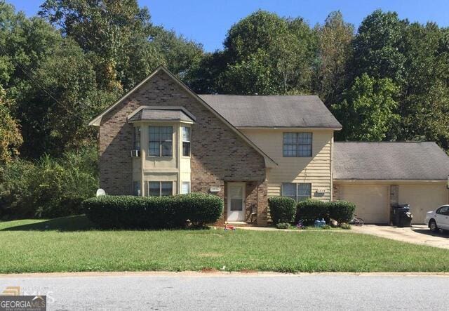 view of front of property featuring brick siding, an attached garage, concrete driveway, and a front lawn