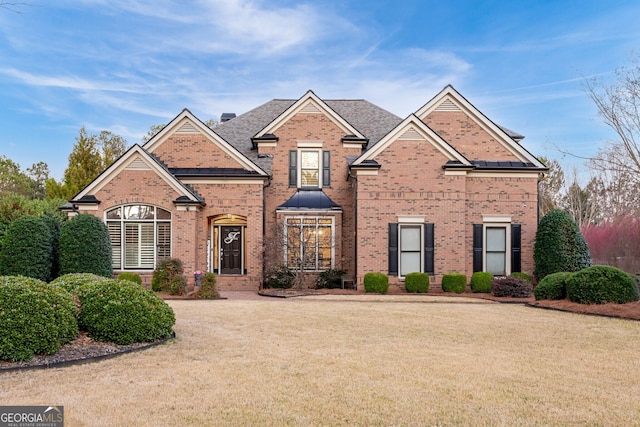 traditional-style house featuring a front lawn and brick siding