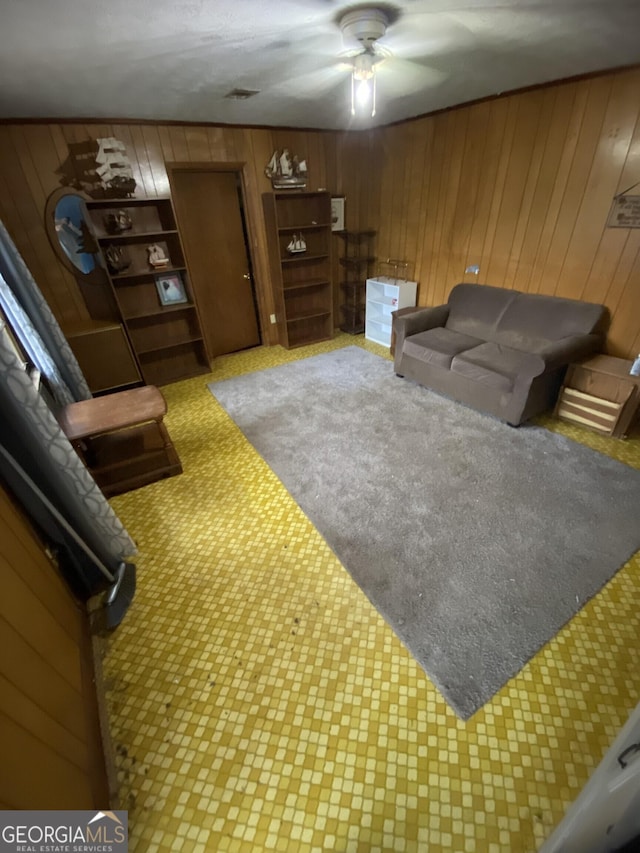 living area featuring wooden walls and a ceiling fan