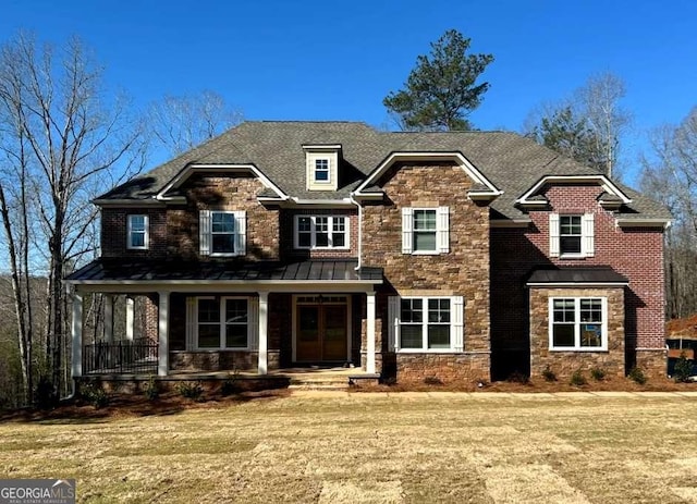 craftsman-style house featuring a front yard, a standing seam roof, a shingled roof, stone siding, and brick siding