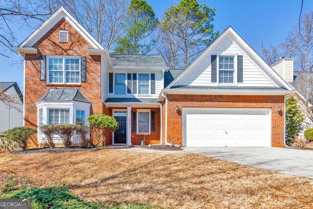 traditional-style home featuring brick siding, a chimney, concrete driveway, and a front yard