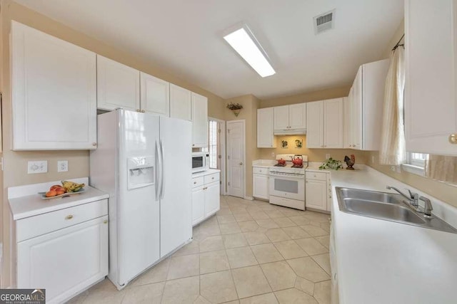 kitchen featuring visible vents, a sink, white appliances, white cabinets, and light countertops