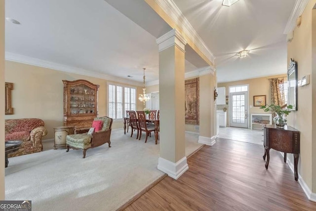 living room with a wealth of natural light, crown molding, an inviting chandelier, and wood finished floors