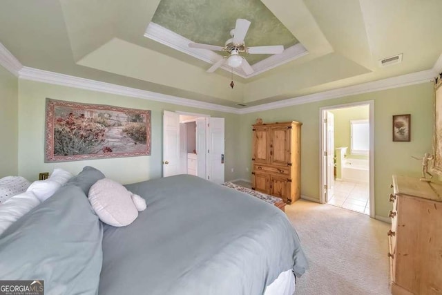 bedroom featuring visible vents, light carpet, ornamental molding, ensuite bathroom, and a tray ceiling