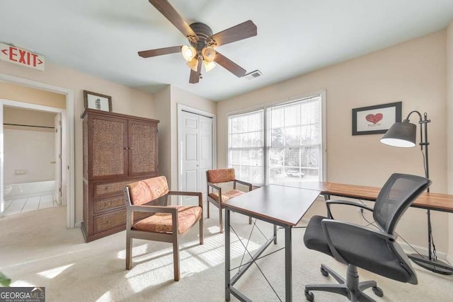 office space with a ceiling fan, visible vents, and light carpet