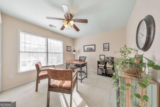 office area with visible vents, light carpet, baseboards, and ceiling fan