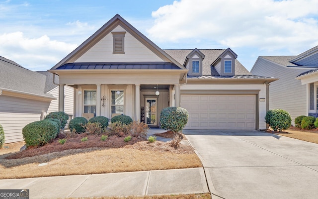 view of front facade with an attached garage, metal roof, a standing seam roof, and concrete driveway