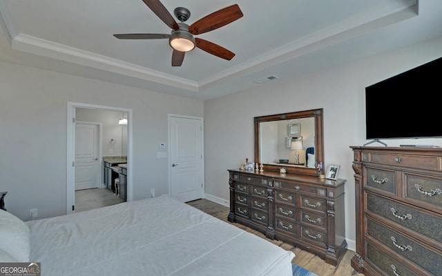 bedroom featuring visible vents, baseboards, a tray ceiling, ornamental molding, and wood finished floors