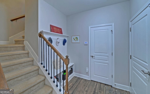 stairway with wood finished floors and baseboards