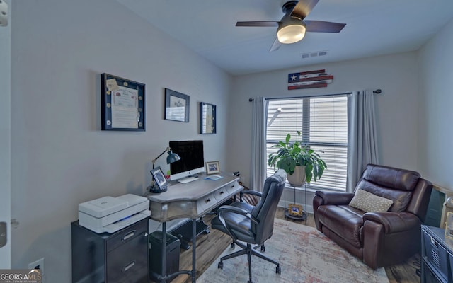 office featuring wood finished floors, a ceiling fan, visible vents, and baseboards