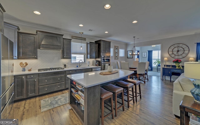 kitchen featuring a kitchen island, custom exhaust hood, a sink, a kitchen bar, and open floor plan